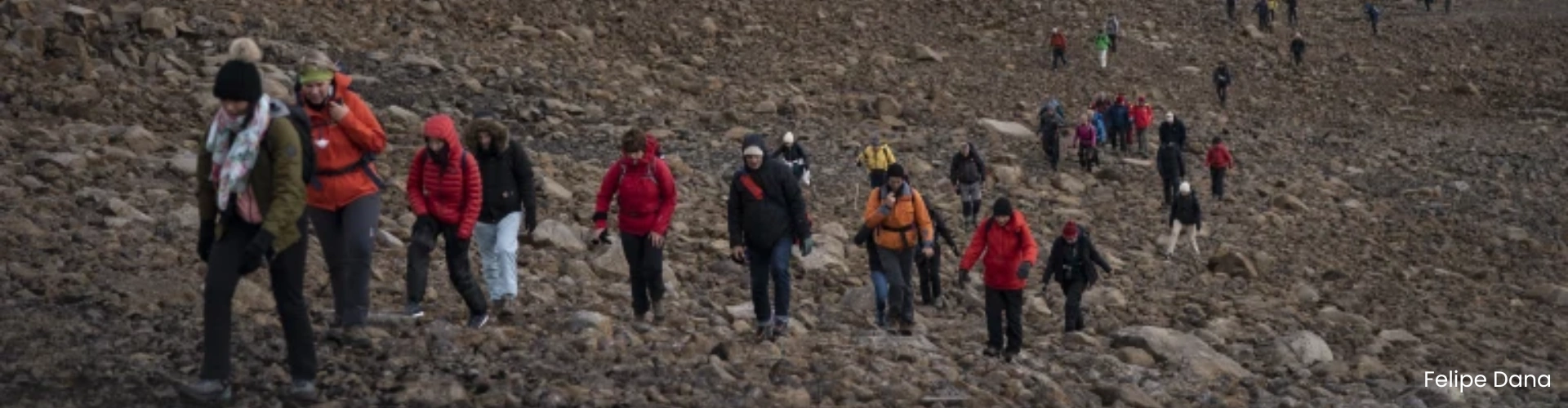 Hikers walking up a usually snowy mountain, instead conditions are dry and rocky as there is no snow from the Heatwave in Iceland