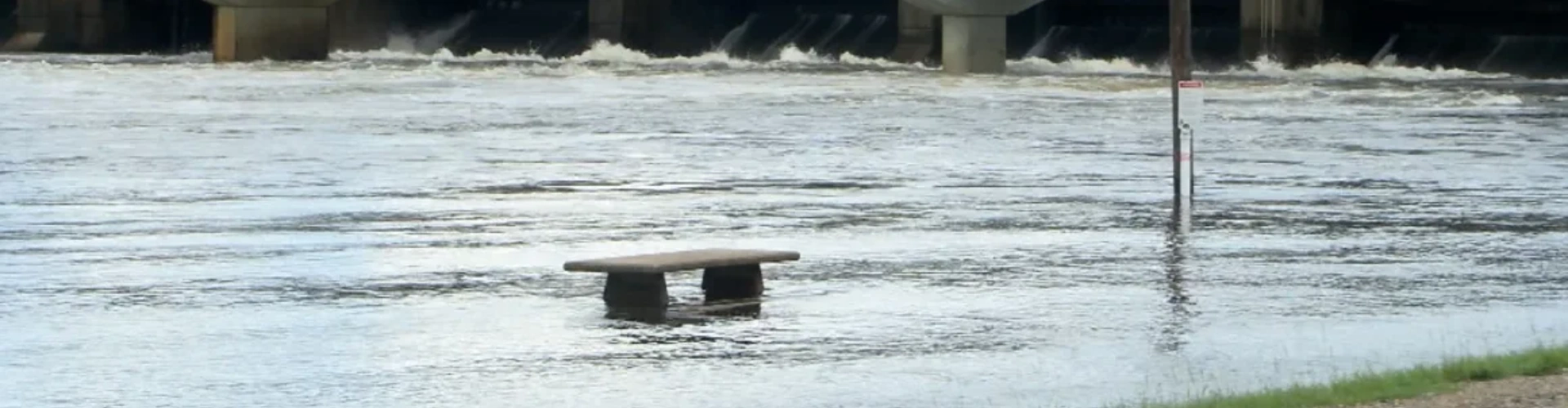 A small stone bench poking out of some deep flood waters after heavy rains in Mississippi