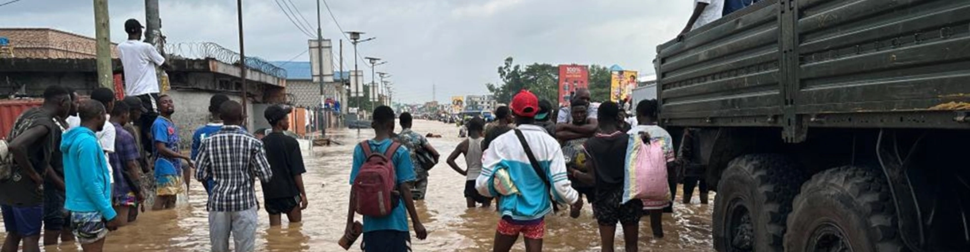 A large crowd stood in knee deep water with a large truck nearby during the floods in Kinshasa Floods