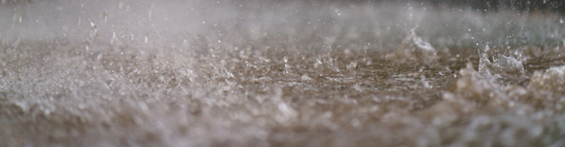 Water splashing in a puddle on a beach from a very close angle, during rainfall in NSW