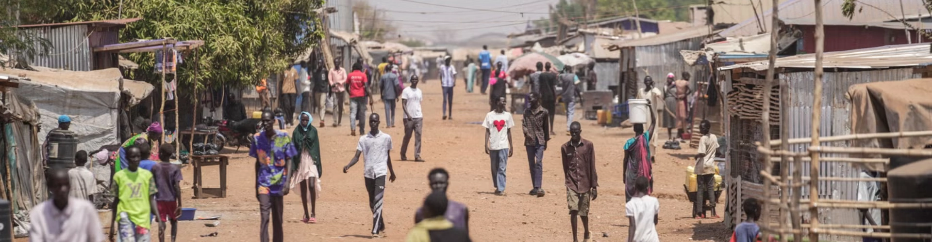 A long, dry street in South Sudan with lots of people walking along in during a heatwave